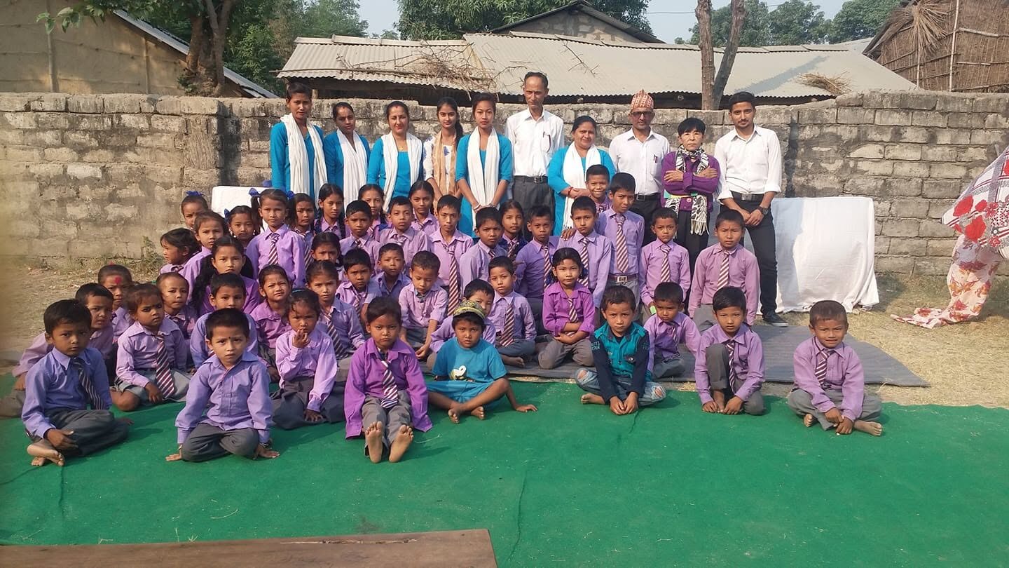 The whole school in the early days, students in purple and teachers in blue and white, posing together on the green mat