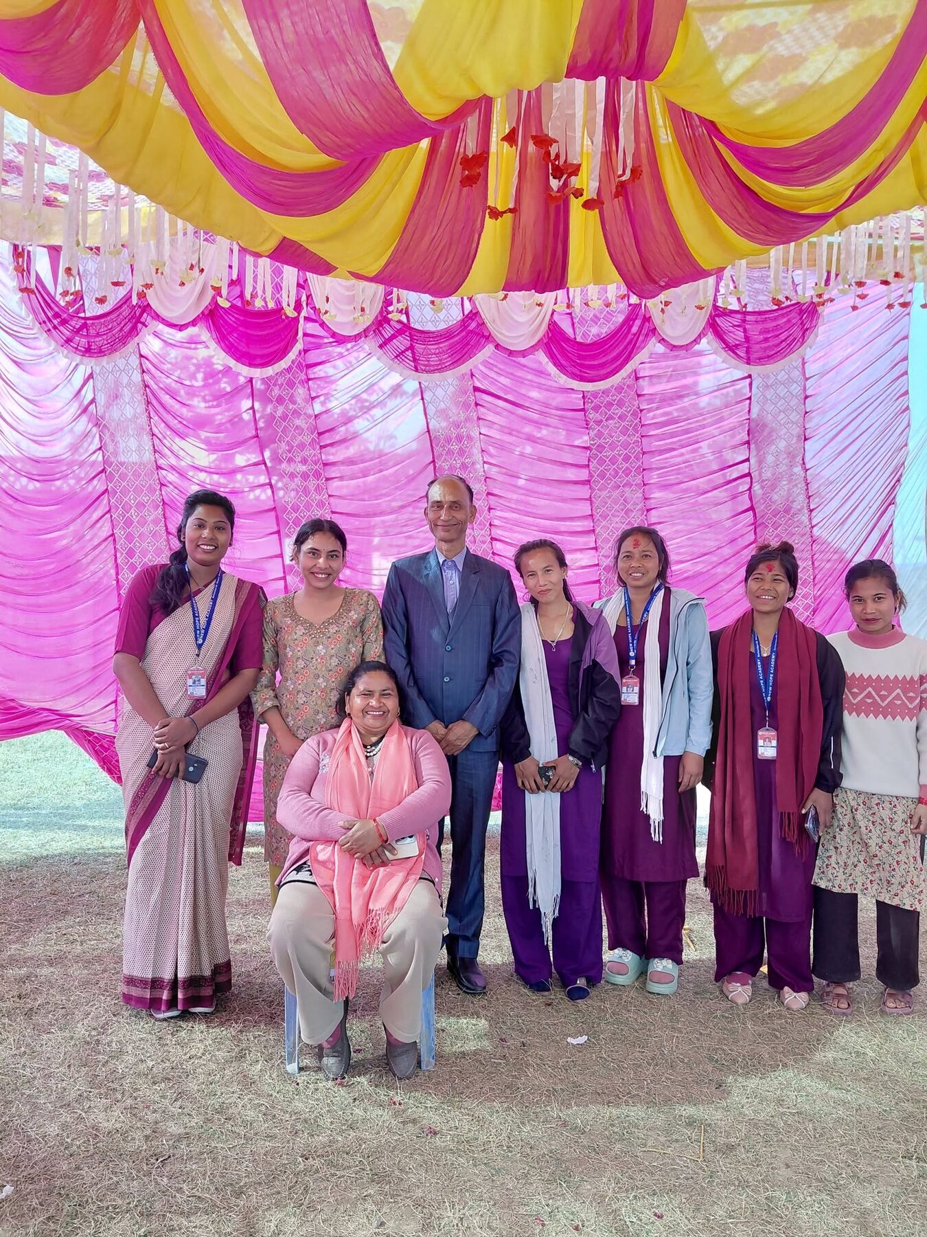 Our teachers and guests standing together under the pink canopy at the annual day celebration